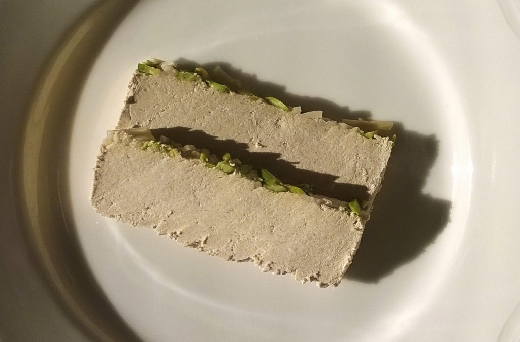 Two slices of Oghab tahini halva with pistachio